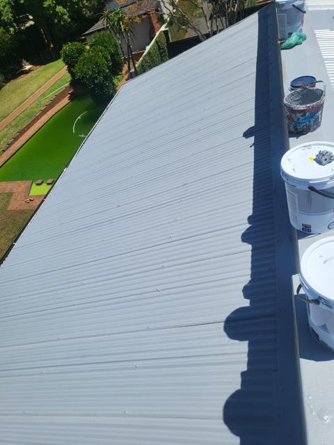 Roof being coated, paint buckets on the ridge